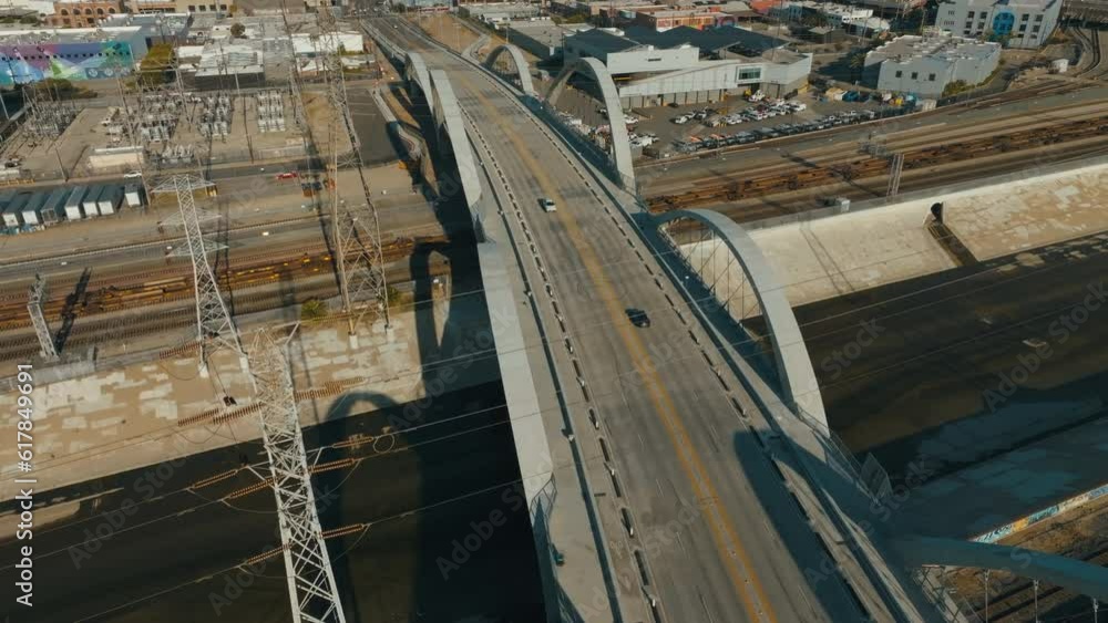 Car driving towards Los Angeles skyline in sunset. Downtown over a bridge with cars driving towards. Aerial drone shot of 6th street bridge in Los Angeles. Car driving towards Los Angeles skyline in sunset. Downtown over a bridge with cars driving towards. Aerial drone shot of 6th street bridge in Los Angeles.
