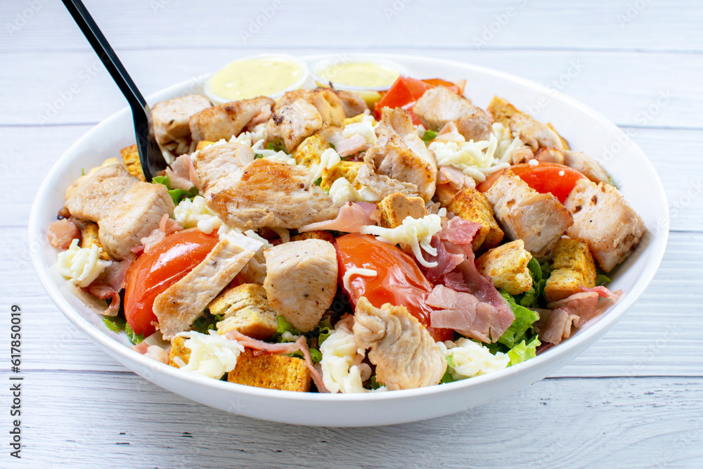 Bowl salad with pieces of roasted pork, grated cheese, beans, corn, tomato, nachos, lettuce, with house mayonnaise