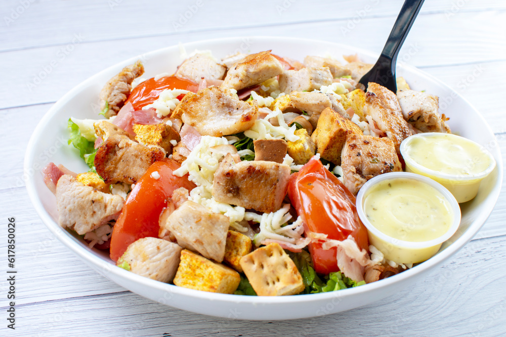 Roasted pork protein salad, accompanied by tomatoes, grated mozzarella cheese, lettuce, bacon, croutons in mayonnaise sauce with mustard