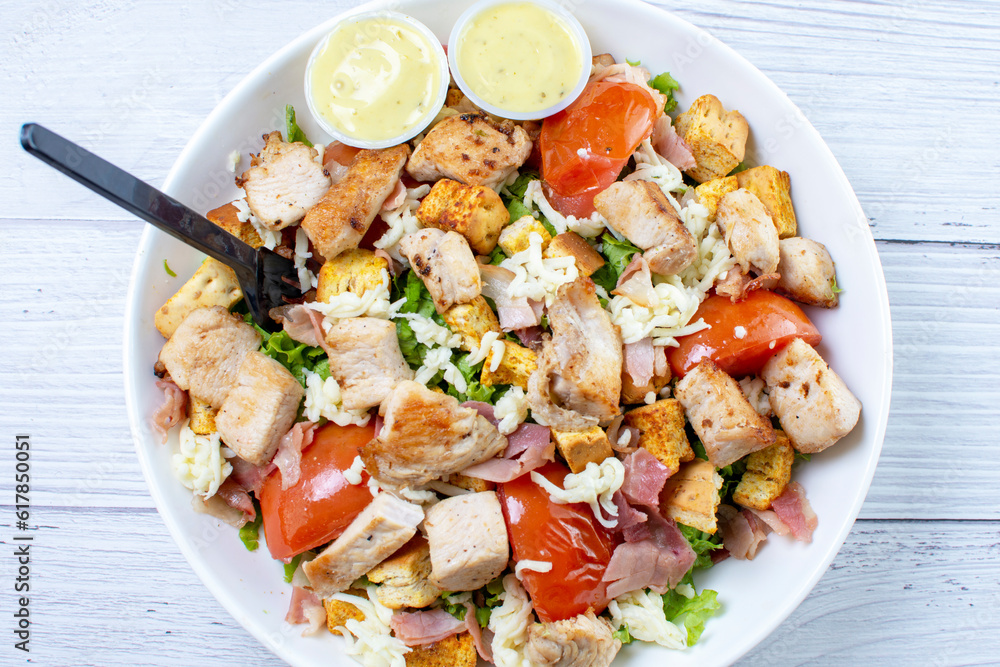 Roasted pork protein salad, accompanied by tomatoes, grated mozzarella cheese, lettuce, bacon, croutons in mayonnaise sauce with mustard