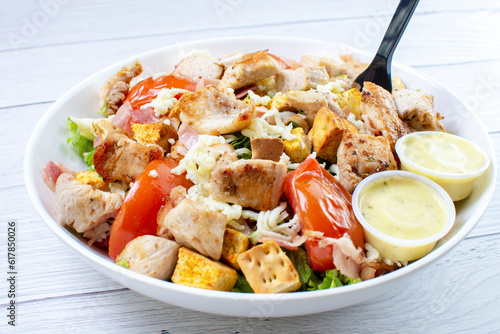 Roasted pork protein salad, accompanied by tomatoes, grated mozzarella cheese, lettuce, bacon, croutons in mayonnaise sauce with mustard