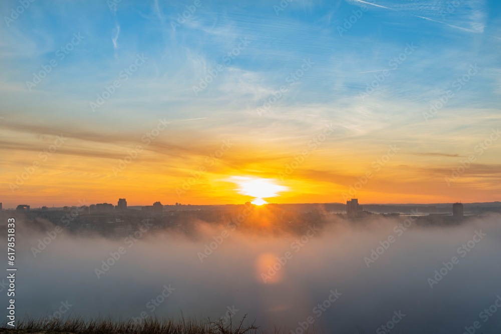 foggy sunrise above city on autumn