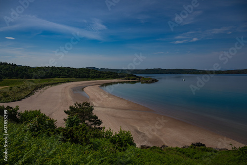 2023-06-09 A SAND BEACH WITH GREEN FOLIAGE AND CALM WATERS IN GAIRLOCH SCOTLAND