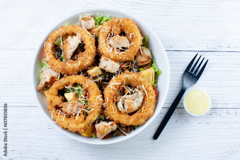 Bowl salad with pieces of roast pork, grated cheese, onion rings and house mayonnaise