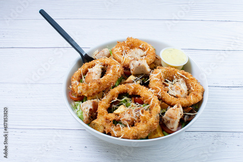 Bowl salad with pieces of roast pork, grated cheese, onion rings and house mayonnaise