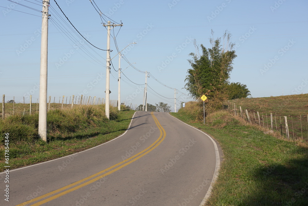 Linda estrada asfaltada com placa de sinalização para ciclista no local.