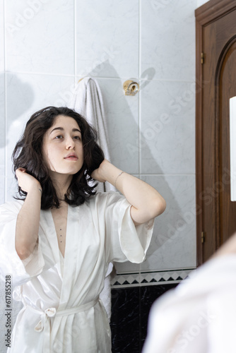 Latin woman in bathroom. Young female playing with her hair in front of a mirror.
