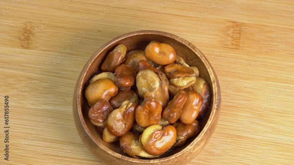 Fried broad bean rotate in wooden bowl. Salty roasted broad bean beer snack, snack food macro