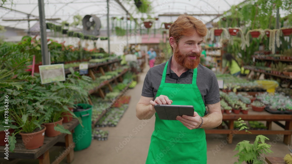 Mobile Male Employee Checking Inventory via Tablet in Flower Shop. Green Aproned Young Man Integrating Modern Tech in Store Operations Mobile Male Employee Checking Inventory via Tablet in Flower Shop. Green Aproned Young Man Integrating Modern Tech in Store Operations