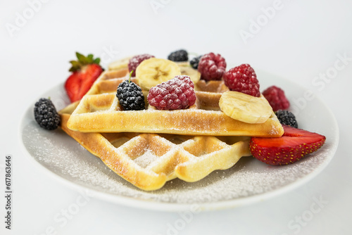 Square Belgian waffles with berries and jam on a light white background.