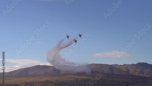 Fighter jets flying in formation with smoke mountains in the background