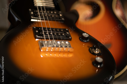 Brown and black electric guitar in front of a acoustic guitar in the background
