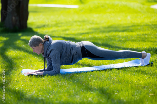 Woman in grey sportswear doing yoga in the park