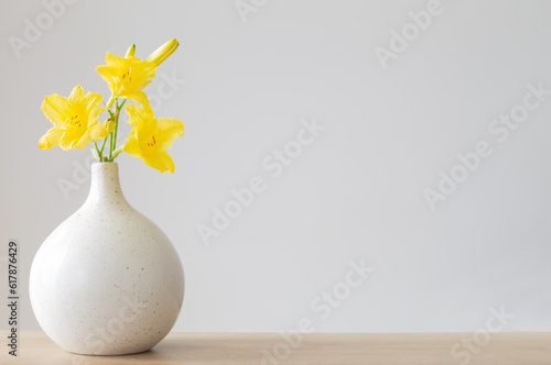 yellow summer flowers in white vase on gray background