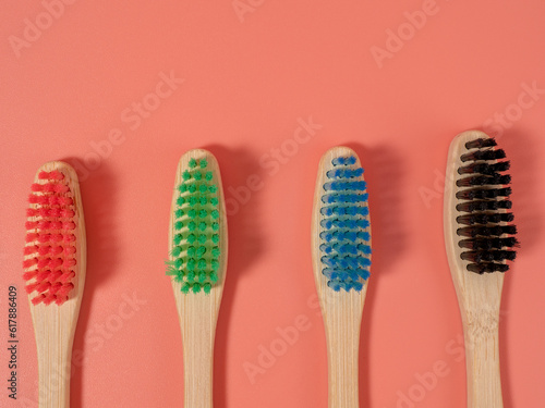 Bamboo toothbrushes in different colors. Wooden toothbrush on a pink background. Toothbrush close-up.