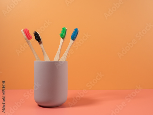 Bamboo toothbrushes in different colors. Wooden toothbrush on an orange background. Toothbrush close-up.