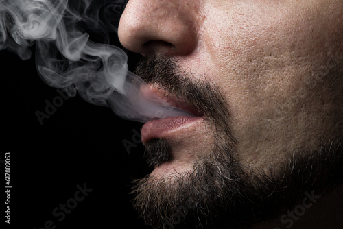Smoke comes out of male lips on a black background
