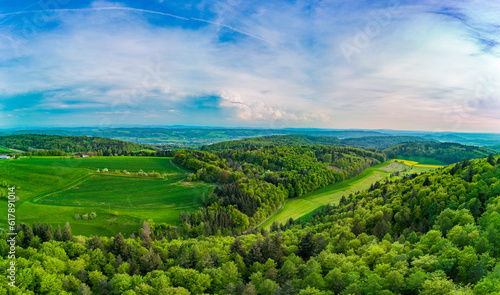 Panorama on valley with meadows, fields, forest and farms against a cloudy sky