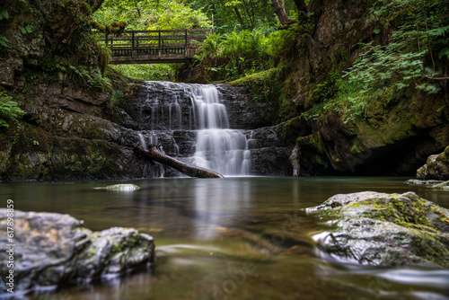 The Sychryd Cascades or Sgydau Sychryd Falls with wooden bridge in the Waterfall Country near the Dinas Rock, Pontneddfechan, Brecon Beacons National Park, South Wales, UK. Long exposure water.