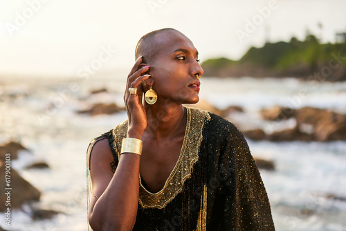 Photos Epatage lgbtq black man poses on scenic ocean beach looks at camera demonstrates jewellery