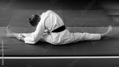 Young Karate Athlete Warming Up on Tatami — Black-and-White Back View Scene with Motion Blur and Copy Space