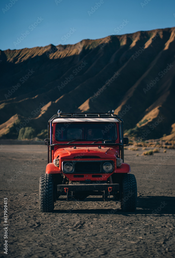 Front view of red jeep with Bromo volcano background. Semeru mountain national park tourist transport