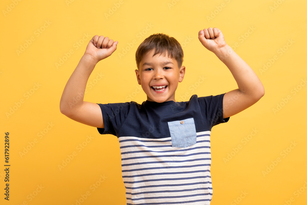 Emotional happy boy raising hands up, clenching fists Emotional happy boy raising hands up, clenching fists