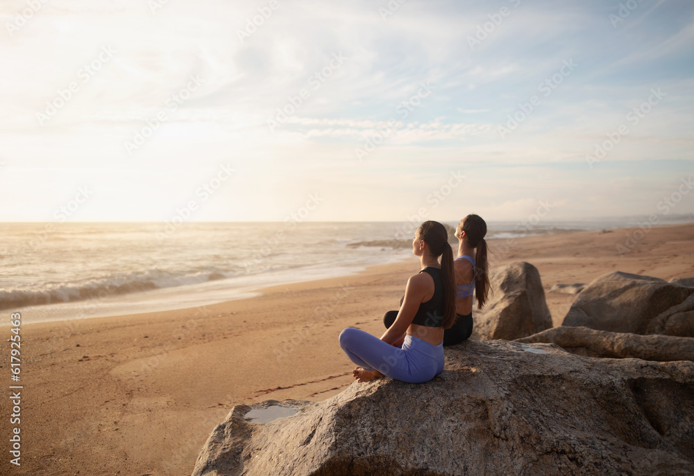 Calm happy young european women twins in sportswear practice yoga on sea beach, enjoy morning peace