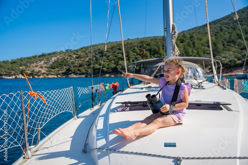 Little girl on a yacht looking through binoculars in the sea