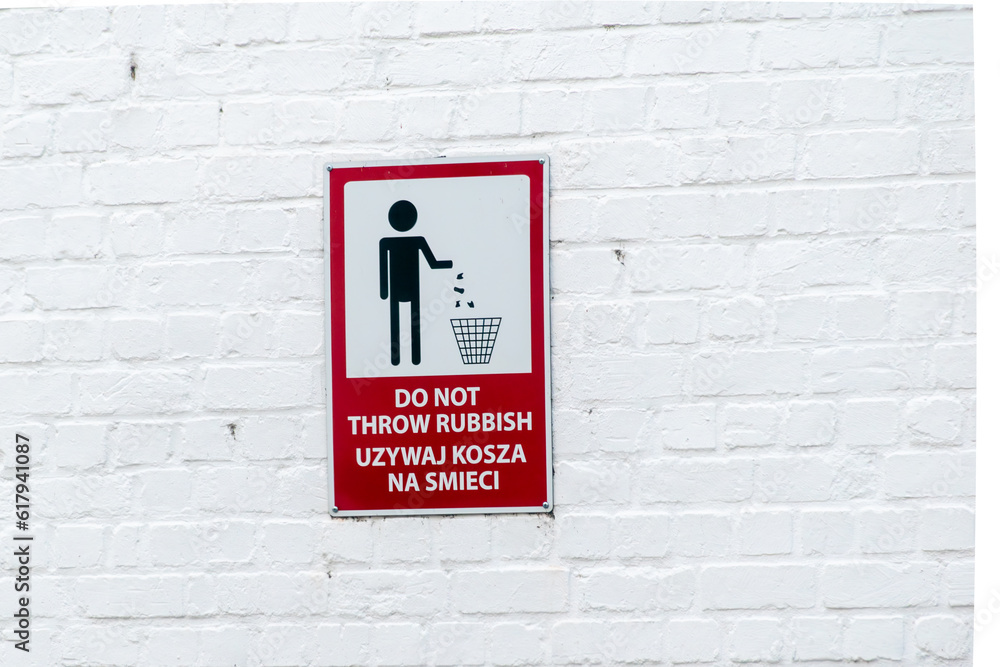 No garbage disposal sign. A banner prohibiting throwing garbage in nature in the area. The sign is on a white wall with the words in English and Polish meaning it is forbidden to throw garbage No garbage disposal sign. A banner prohibiting throwing garbage in nature in the area. The sign is on a white wall with the words in English and Polish meaning it is forbidden to throw garbage