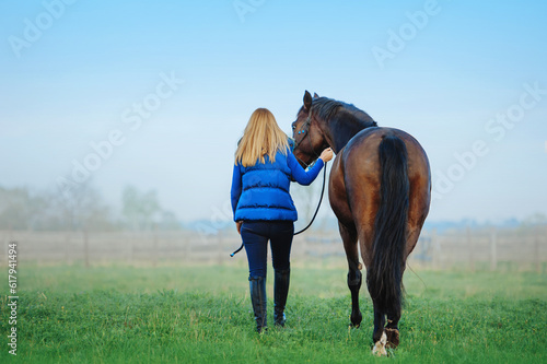 Horse and woman walking away to the field © Tetiana Yurkovska