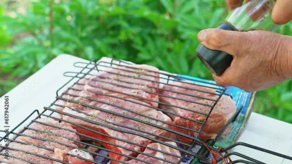 Meat steaks are sprinkled with spices on a grill rack. Cooking over an open fire Meat steaks are sprinkled with spices on a grill rack. Cooking over an open fire