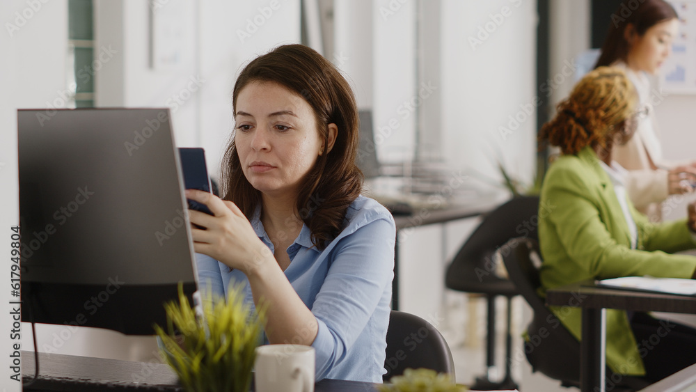 Successful businesswoman taking social media break at desk, checking online website on smartphone app. Young manager using mobile phone and planning project for investment. Handheld shot. Successful businesswoman taking social media break at desk, checking online website on smartphone app. Young manager using mobile phone and planning project for investment. Handheld shot.