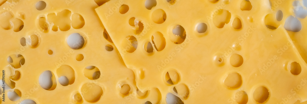 Close-up of a piece of cheese in a hole on a plate close-up. View from above. Long banner Close-up of a piece of cheese in a hole on a plate close-up. View from above. Long banner