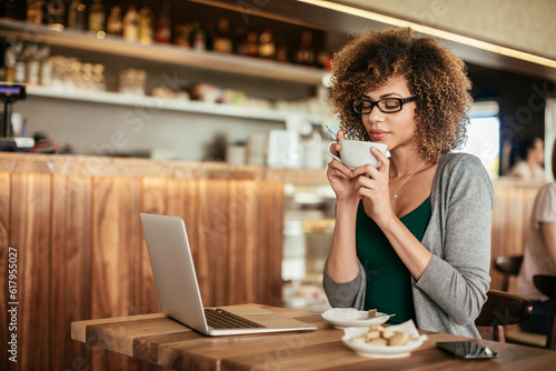 Young woman enjoying a coffee while using a laptop in a cafe