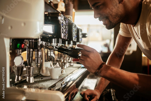 Young male barista making a coffee in a cafe