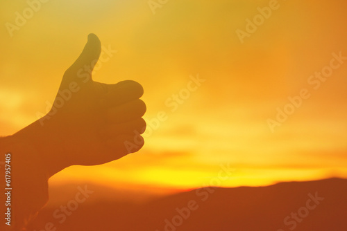 Thumbs up on golden nature sunrise background 