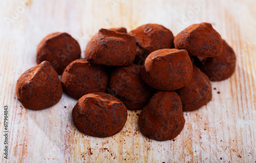 Chocolate truffles in cocoa powder on wooden background