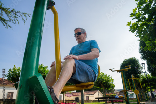 Hombre de la tercera edad haciendo flexiones de piernas en una máquina deportiva. photo