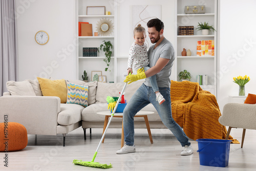 Spring cleaning. Father and daughter having fun while tidying up together at home