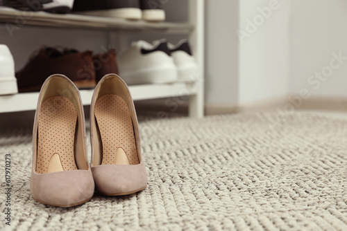 Orthopedic insoles in high heel shoes on rug. Space for text