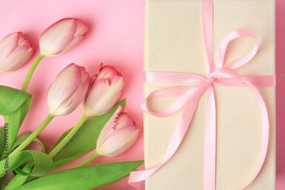 Beautiful gift box with bow and tulips on pink background, flat lay Beautiful gift box with bow and tulips on pink background, flat lay