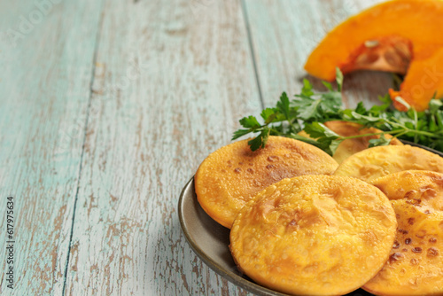 Fotografia Sopaipillas in round plate on wooden table, pumpkin or squash in the bottom and parsley, copy space