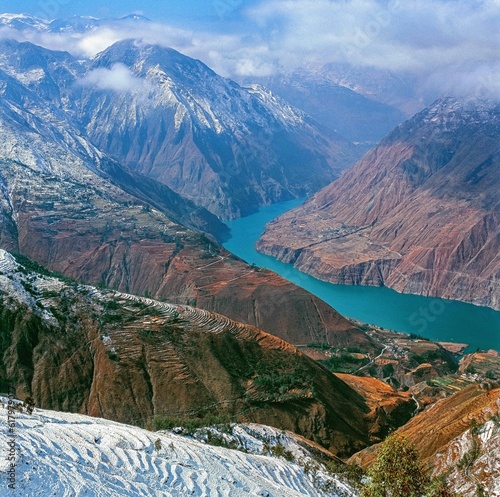 Turquoise colored river bends around snow covered mountains 