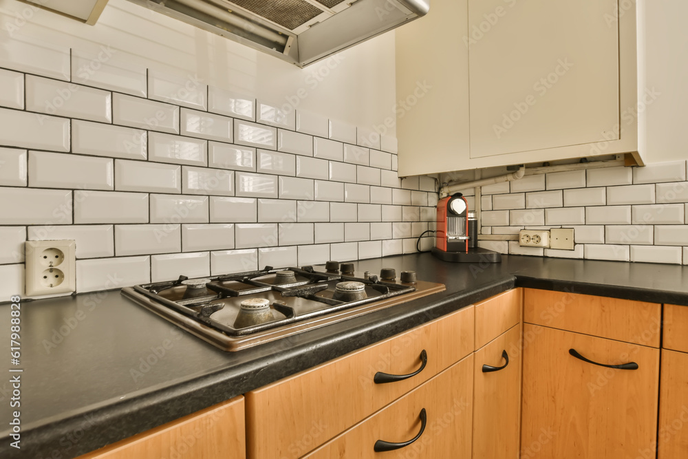 a kitchen with black counter tops and white subway tiles on the wall behind it is an oven, toaster and dishwasher a kitchen with black counter tops and white subway tiles on the wall behind it is an oven, toaster and dishwasher
