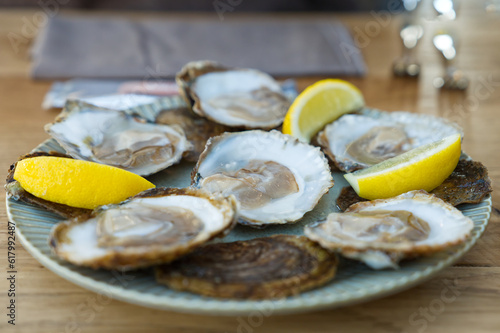 Fresh oysters served on a plate with lemon on old wooden table. Teasty Oysters served in fish restaurant. photo