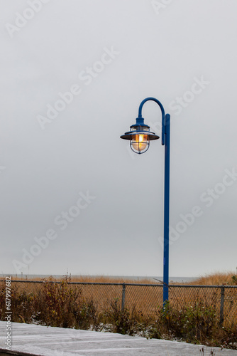 vue sur un lampadaire en métal bleu avec la lumière allumée derrière un grillage et un abat jour en soucoupe photo