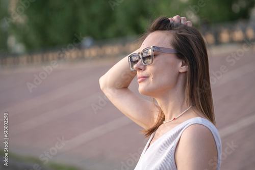 Summer urban portrait of a young brunette woman in sunglasses.