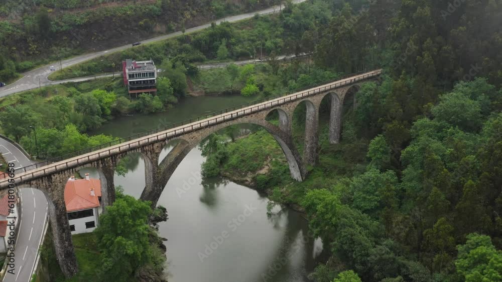 Aerial: Poço de Santiago Bridge over Serene Sever do Vouga River and Winding Road, Portugal Aerial: Poço de Santiago Bridge over Serene Sever do Vouga River and Winding Road, Portugal