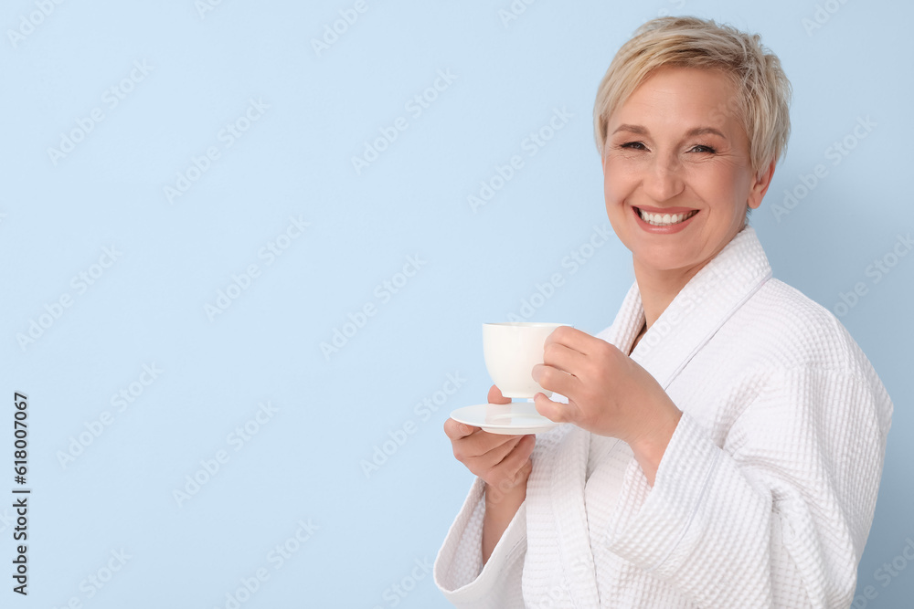 Mature woman in bathrobe with cup of coffee on blue background Mature woman in bathrobe with cup of coffee on blue background